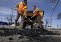 Crew Leader Denny Pitchellis and Equipment Operator Jeremy Turner fill giant potholes on Clyde Park in Wyoming, where there are now signs warning drivers of the hazardous road conditions.
Press Photo/Katy Batdorff