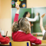 Children Raising Hands In Class, Rear View